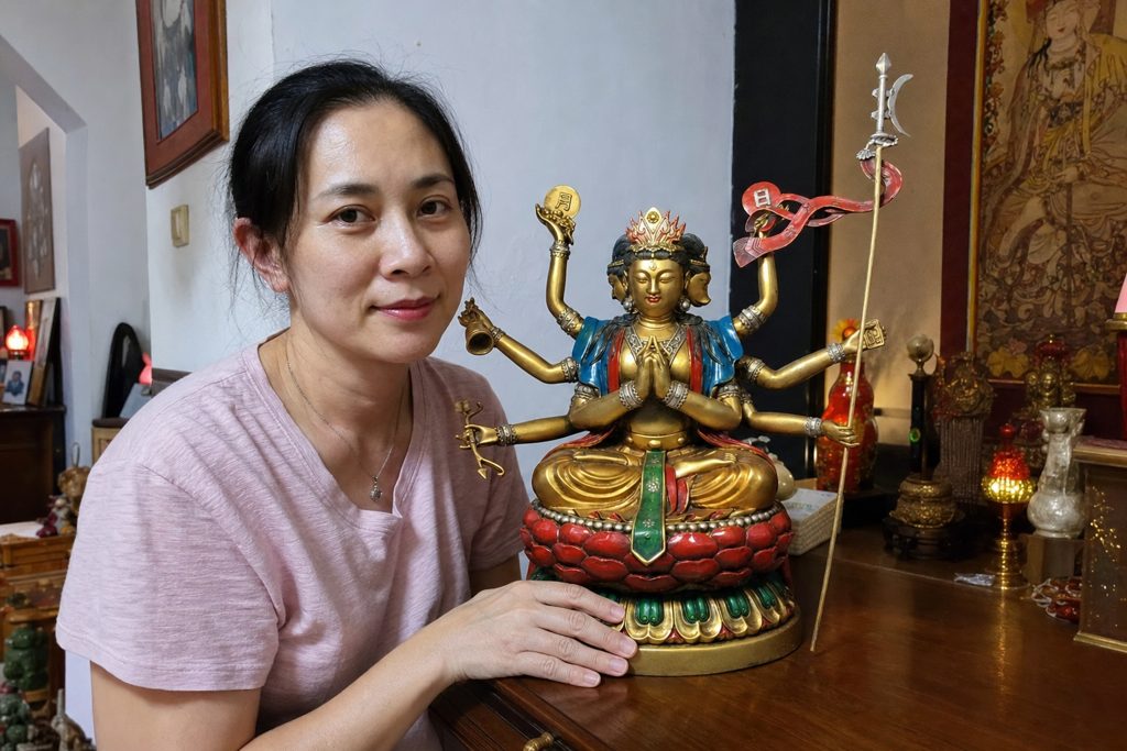Doumu Yuanjun Taoist statue supported by a Chinese woman in a home altar setting