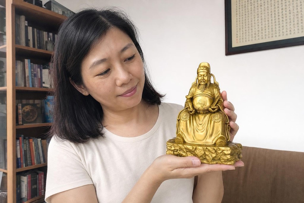Wenchang Dijun statue held by a Chinese woman in a home study setting